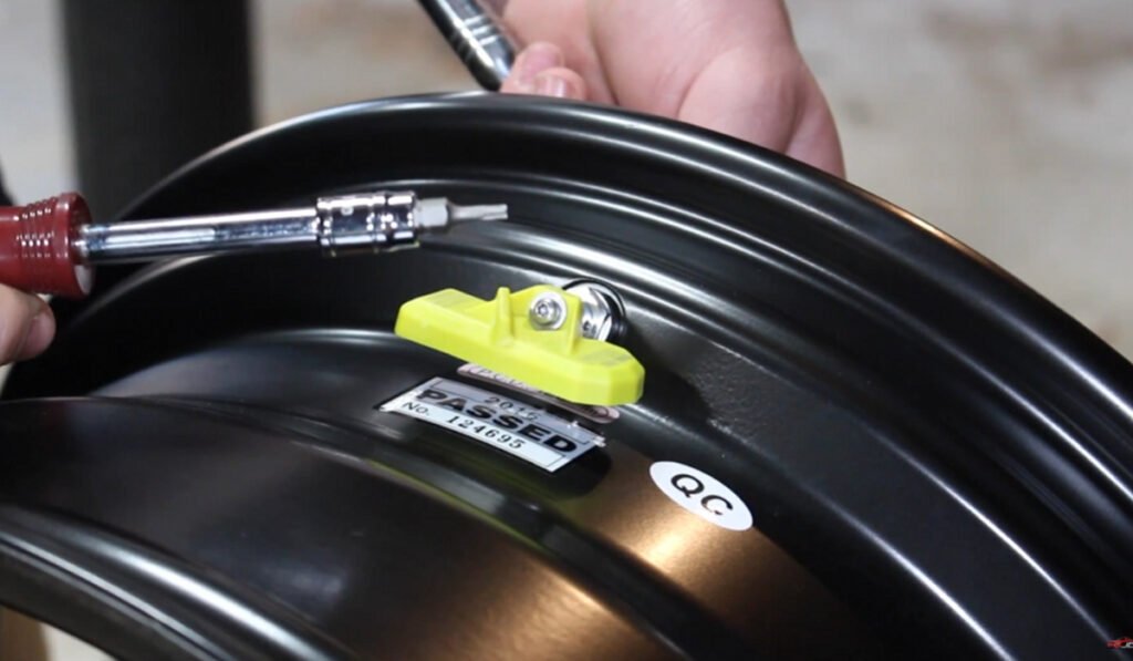 Technician using torque wrench to tighten TPMS valve stem – how to program TPMS sensors safely