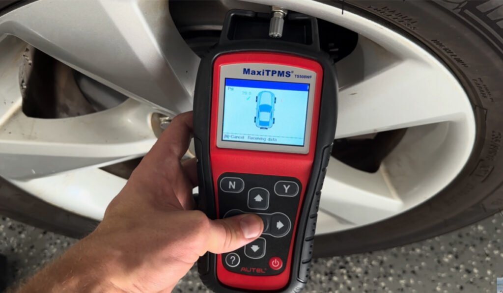 Mechanic holding a TPMS diagnostic tool during inspection – TPMS sensor replacement cost